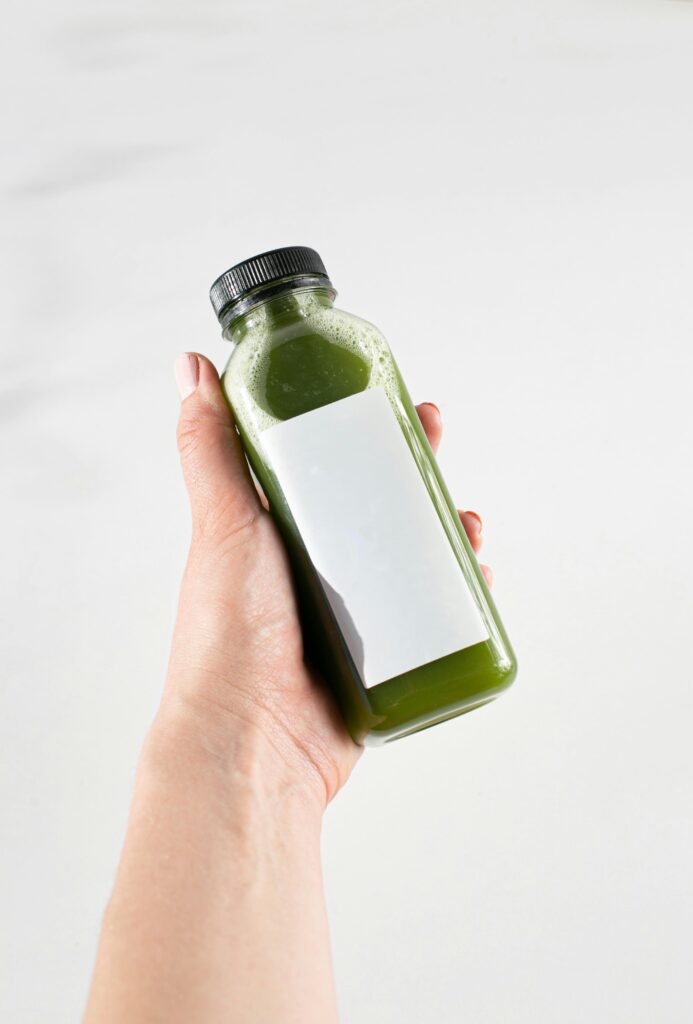 Ręka trzymająca butelkę z zielonym płynem - probiotyki naturalne w płynie