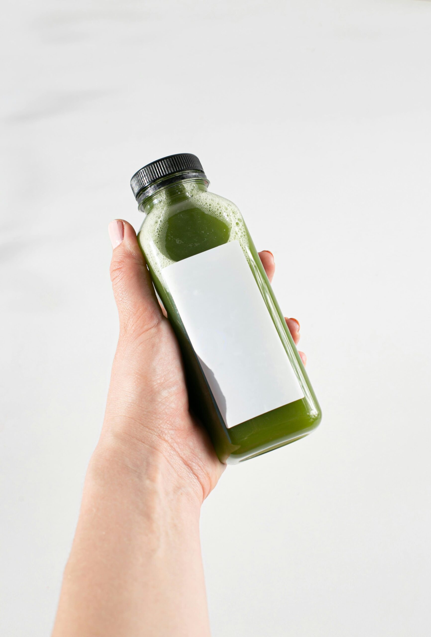 Ręka trzymająca butelkę z zielonym płynem - probiotyki naturalne w płynie
